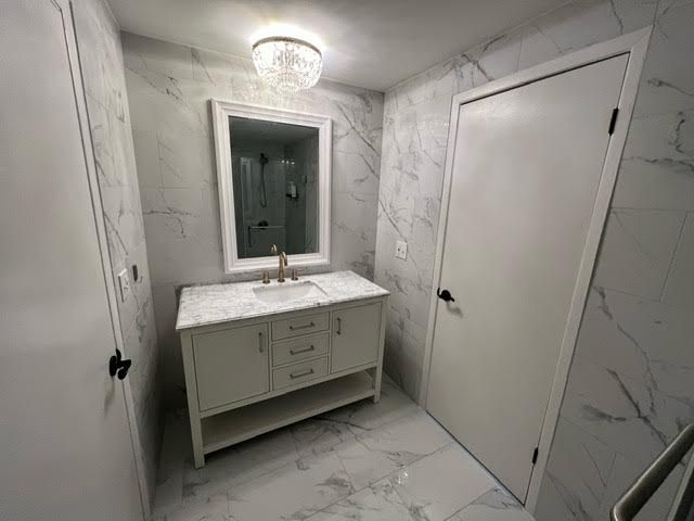 1622 Brentwood Dr, Troy, MI 48098 - bathroom featuring marble look tiles, vanity, and a chandelier