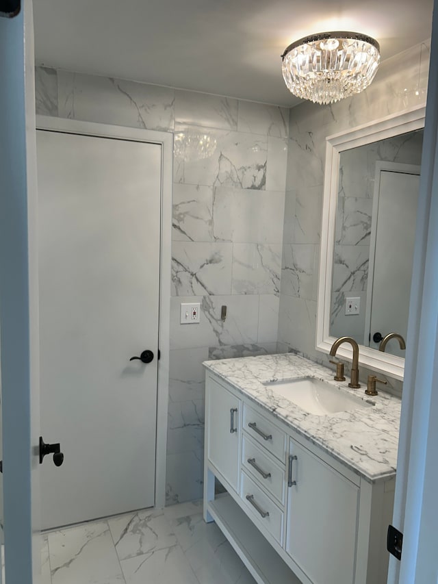 bathroom featuring vanity, a notable chandelier, and tile walls