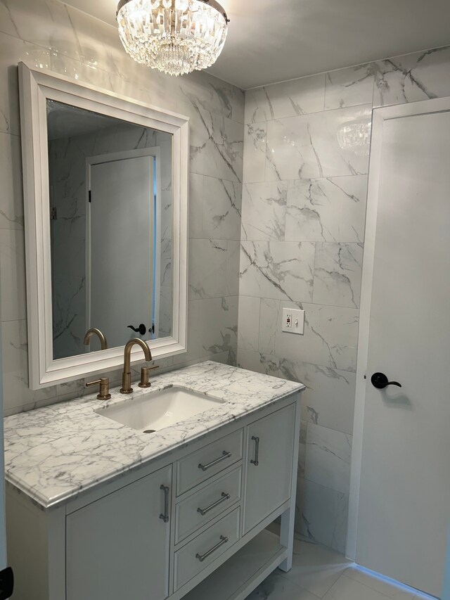 bathroom with vanity, a chandelier, and tile walls