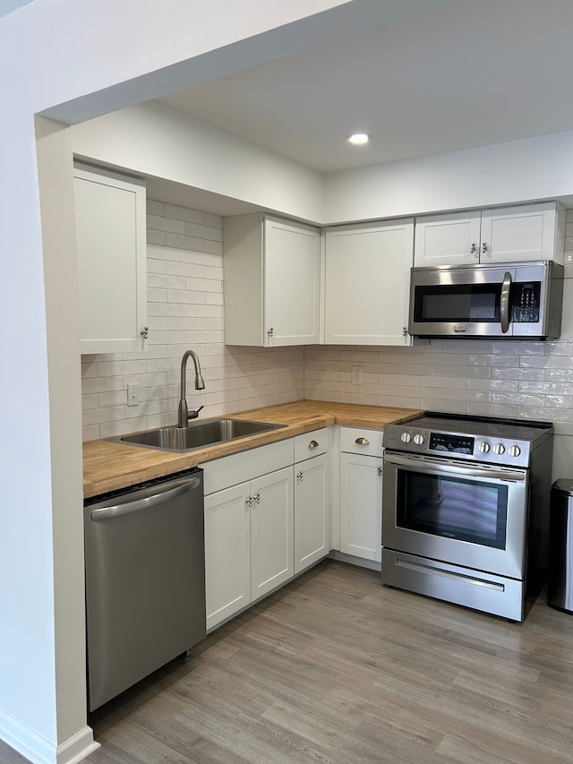 kitchen featuring sink, butcher block countertops, white cabinetry, light wood-type flooring, and stainless steel appliances