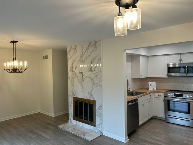 1622 Brentwood Dr, Troy, MI 48098 - kitchen with stainless steel appliances, a sink, a chandelier, and wood finished floors