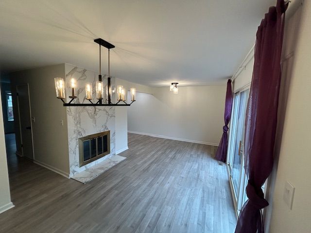 1622 Brentwood Dr, Troy, MI 48098 - unfurnished living room with wood finished floors, a chandelier, a premium fireplace, and baseboards