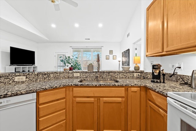 kitchen with ceiling fan, sink, dark stone counters, vaulted ceiling, and white appliances