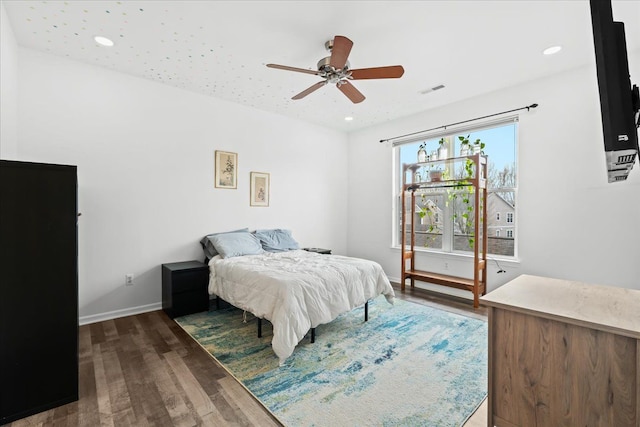 bedroom featuring ceiling fan, dark hardwood / wood-style floors, and multiple windows