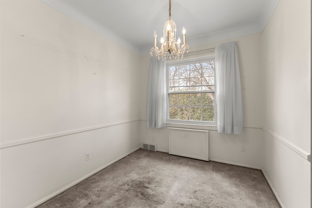 carpeted empty room with a chandelier