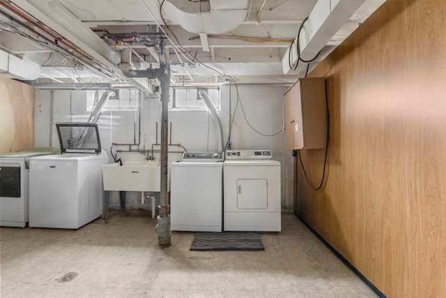 laundry area featuring washing machine and dryer, sink, and wooden walls