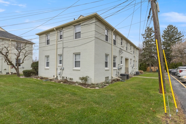 view of side of property featuring central AC unit and a lawn