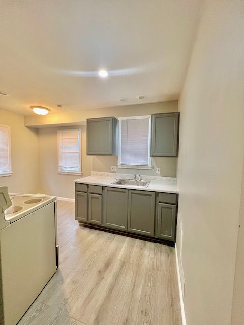 kitchen with light hardwood / wood-style floors, stove, and sink