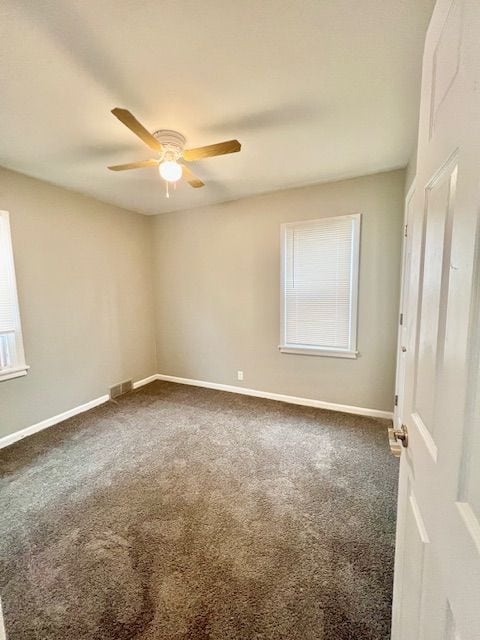 carpeted spare room featuring a wealth of natural light and ceiling fan