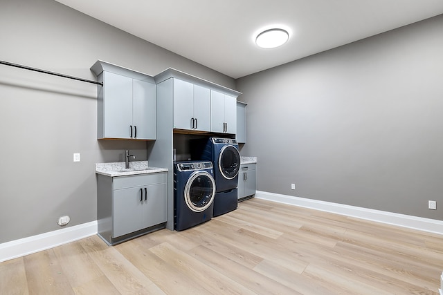 laundry room with cabinets, independent washer and dryer, light hardwood / wood-style flooring, and sink