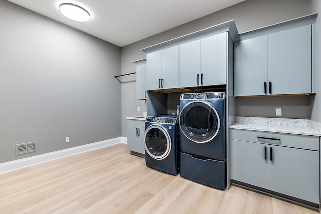 washroom with washer and clothes dryer, cabinets, and light wood-type flooring