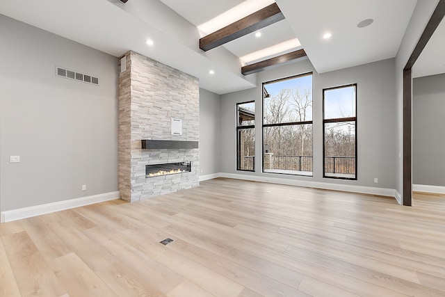 unfurnished living room featuring beam ceiling, light hardwood / wood-style floors, and a fireplace