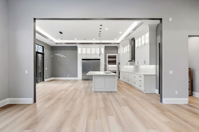 kitchen featuring stainless steel fridge, a tray ceiling, pendant lighting, white cabinets, and a kitchen island