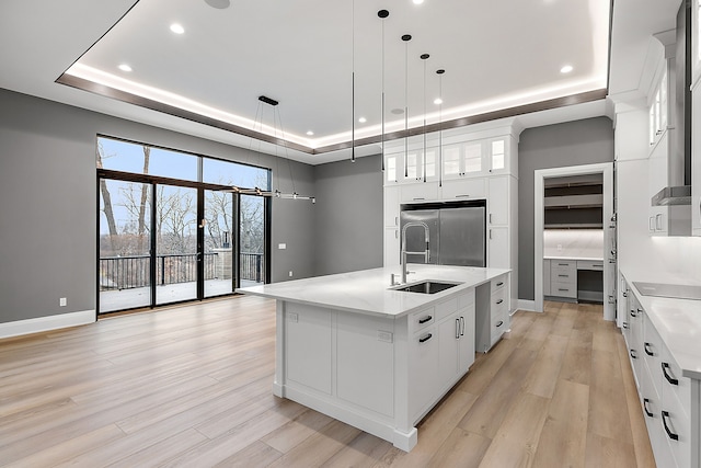 kitchen featuring white cabinets, pendant lighting, a tray ceiling, and a large island