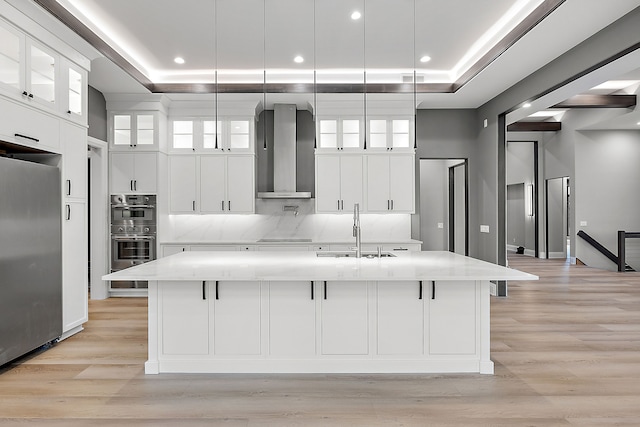 kitchen with a large island, wall chimney exhaust hood, and hanging light fixtures