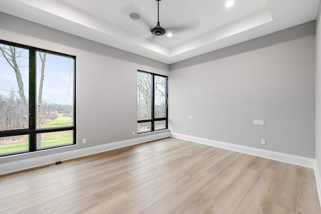 empty room featuring light hardwood / wood-style floors, a raised ceiling, and ceiling fan