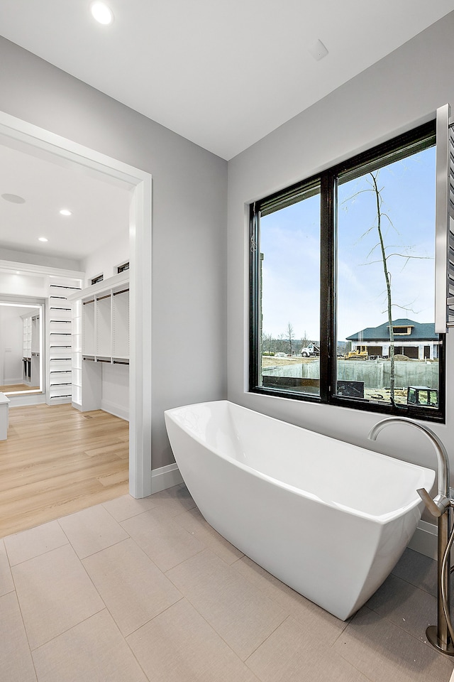 bathroom with tile patterned flooring, a bath, and a water view