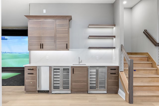 bar featuring wine cooler, sink, light hardwood / wood-style floors, and fridge