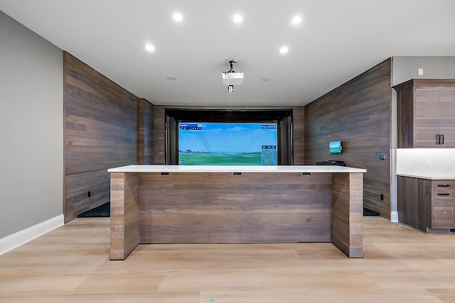 bar with dark brown cabinetry, wooden walls, and light wood-type flooring