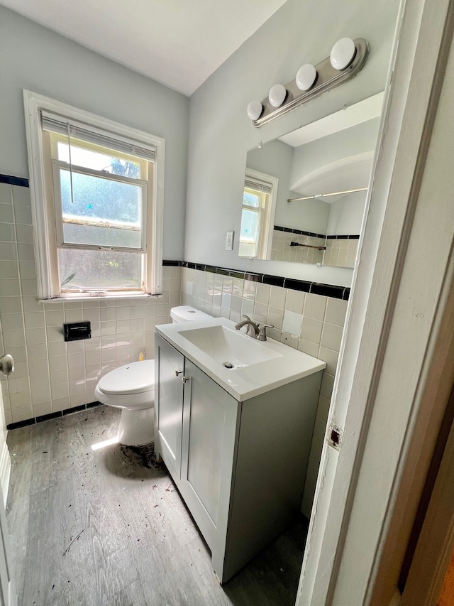 bathroom featuring toilet, vanity, plenty of natural light, and tile walls