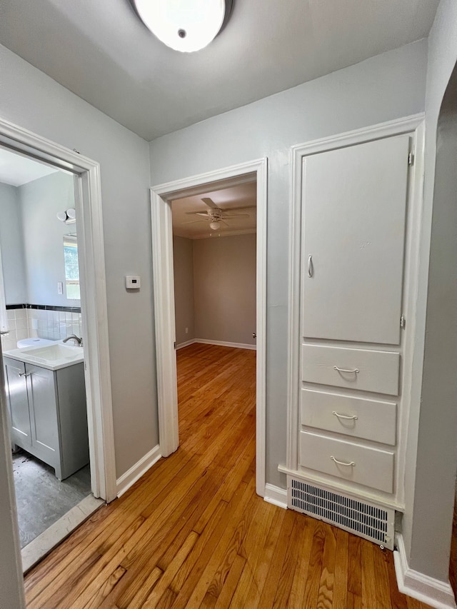 corridor with light hardwood / wood-style flooring and sink