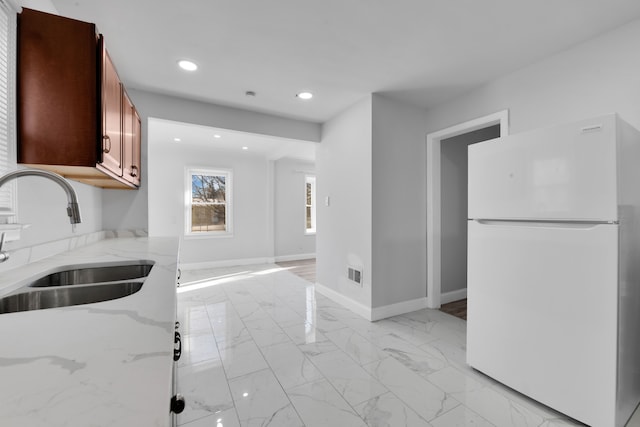 kitchen featuring sink, light stone countertops, and white refrigerator