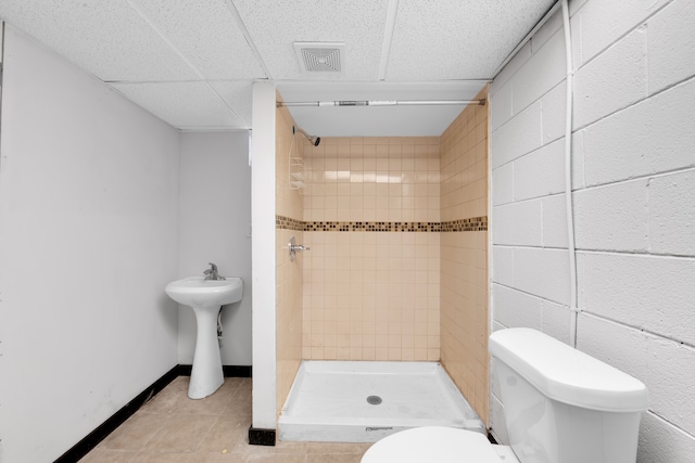 bathroom featuring a tile shower, tile patterned floors, and toilet