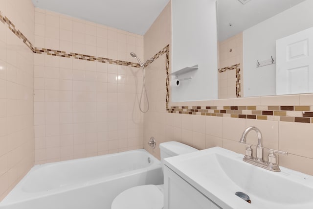 full bathroom featuring tiled shower / bath combo, vanity, tile walls, and toilet