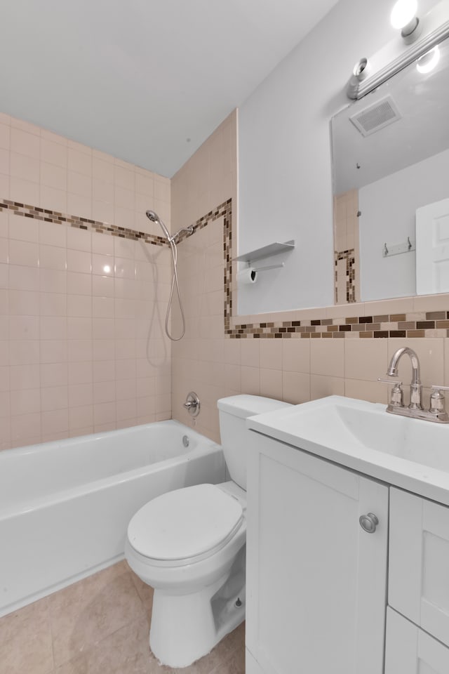 full bathroom with tile patterned floors, toilet, tiled shower / bath, tile walls, and vanity