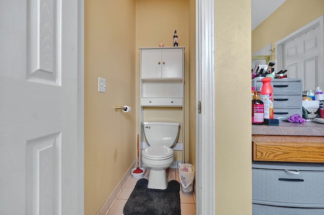 bathroom featuring baseboards, tile patterned floors, and toilet