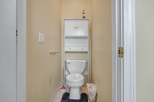 bathroom with toilet, baseboards, and tile patterned flooring