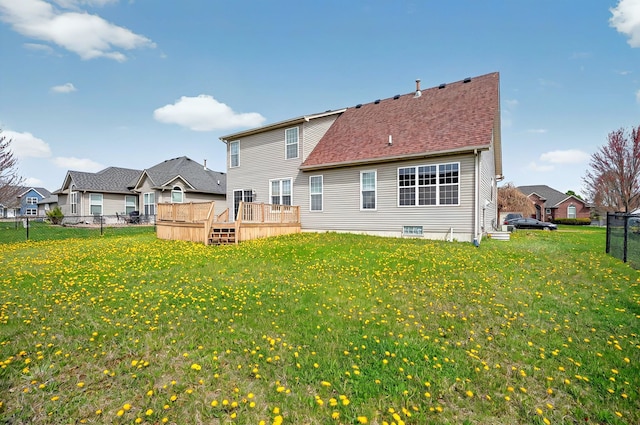 rear view of property featuring a shingled roof, fence, a yard, and a deck