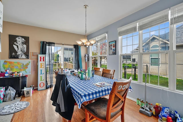 dining space featuring light wood-style floors, baseboards, and a notable chandelier