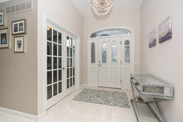 foyer with light tile patterned flooring, an inviting chandelier, and french doors