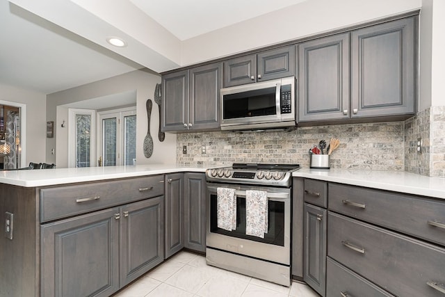 kitchen featuring tasteful backsplash, stainless steel appliances, kitchen peninsula, and light tile patterned flooring