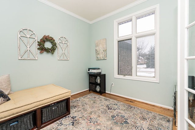 sitting room with a healthy amount of sunlight, ornamental molding, and hardwood / wood-style floors