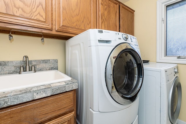 clothes washing area with cabinets, sink, and washing machine and clothes dryer