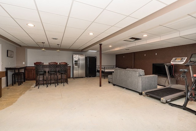 living room featuring a paneled ceiling, concrete flooring, and bar area