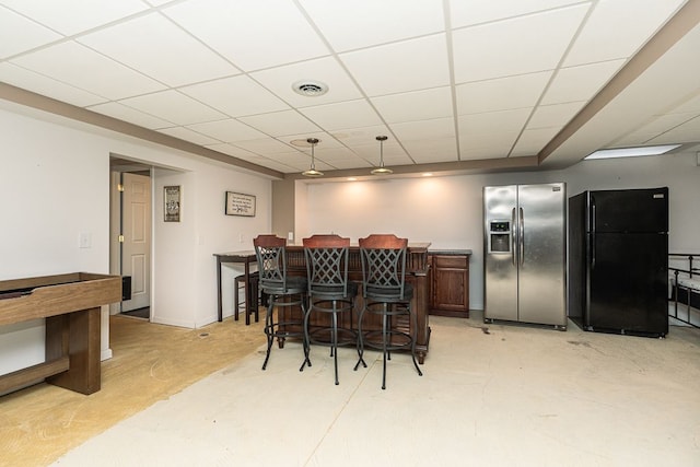 bar featuring black refrigerator, stainless steel fridge, and a drop ceiling