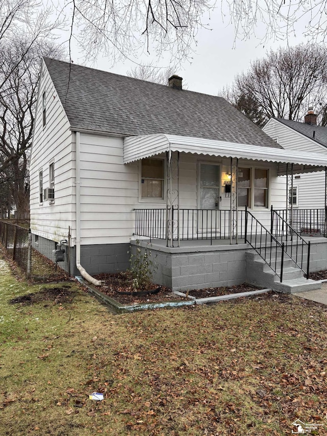 view of front facade featuring cooling unit, covered porch, and a front yard