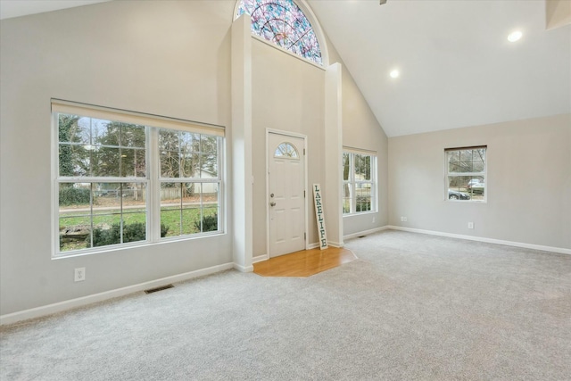 unfurnished living room featuring light carpet, baseboards, visible vents, high vaulted ceiling, and recessed lighting