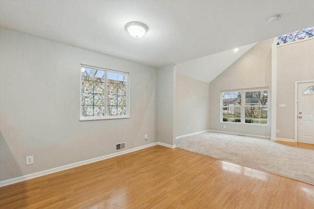 interior space with light wood-type flooring, visible vents, lofted ceiling, and baseboards