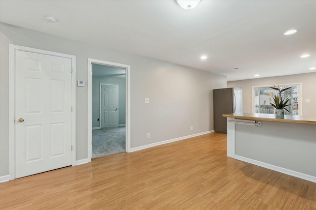 unfurnished living room featuring light wood-style flooring, baseboards, and recessed lighting