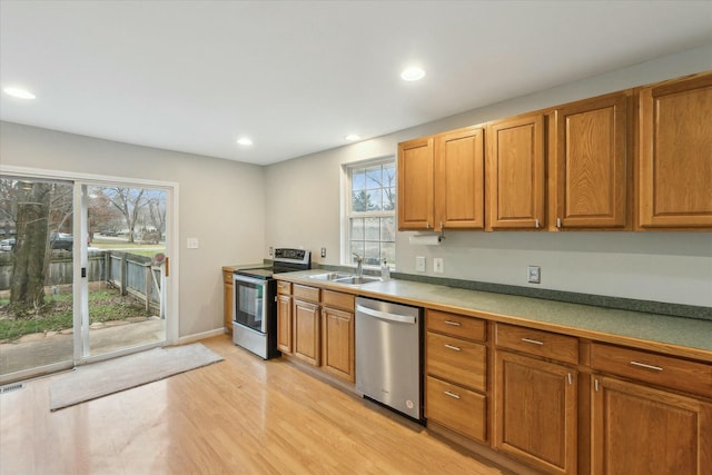 kitchen with stainless steel appliances, light wood-type flooring, a sink, and recessed lighting