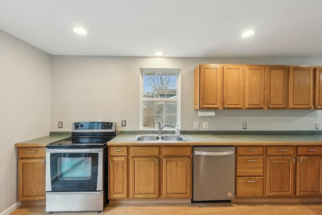 kitchen with light countertops, appliances with stainless steel finishes, a sink, and light wood-style floors