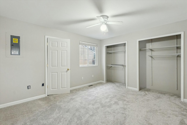 unfurnished bedroom with light carpet, baseboards, and two closets