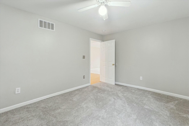 unfurnished room with baseboards, a ceiling fan, visible vents, and light colored carpet