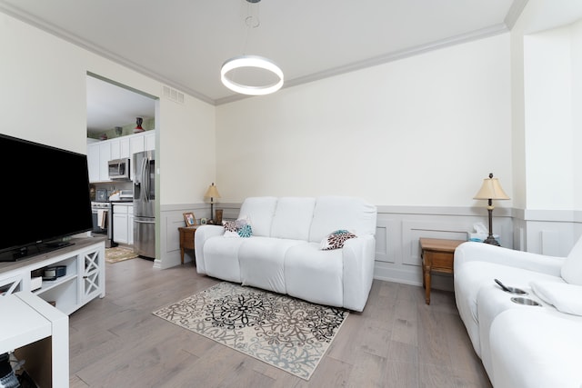 living room featuring light wood-type flooring and crown molding