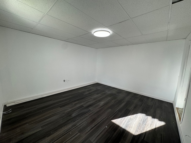 spare room with a paneled ceiling and dark hardwood / wood-style floors