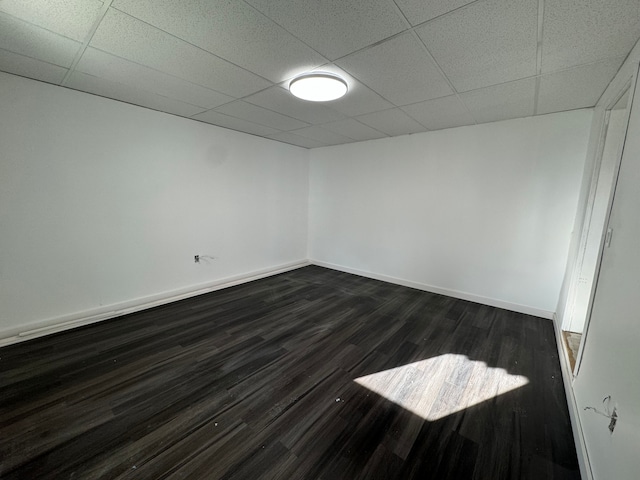 spare room featuring a paneled ceiling and dark hardwood / wood-style floors